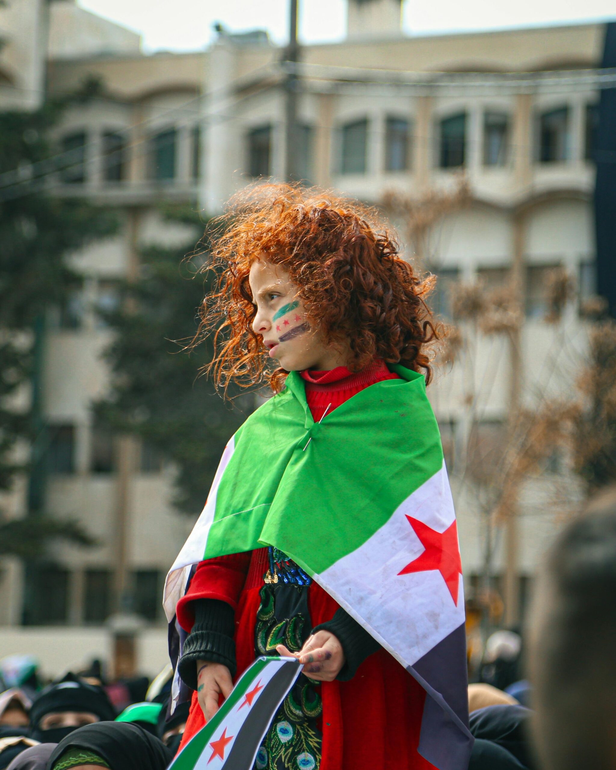 pexels-photo-15957420-15957420 A child with face paint and Syrian flag participates in a public demonstration in Syria.